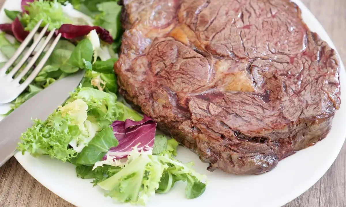 Une succulente côte de bœuf, parfaitement saisie, accompagnée d'une salade fraîche et croquante. Un délice à savourer !