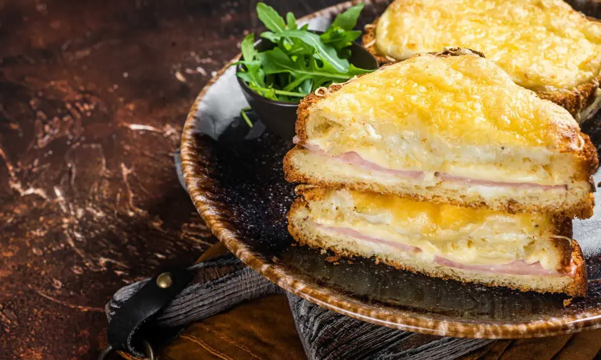 Deux croque monsieur bechamel dorés, garnis de jambon et de fromage fondant, servis avec une salade verte.