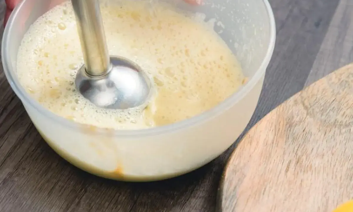Préparation d'une recette mayonnaise maison avec un mixeur plongeant dans un bol. La texture commence à s'épaissir.