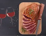 Quel vin avec magret de canard ? Deux verres de vin rouge et un magret de canard tranché sur une planche en bois, prêts à être dégustés.