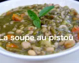 Un bol de soupe au pistou, garni de basilic frais, avec des haricots blancs, des pâtes et des carottes.
