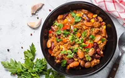 Un bol de chili sin carne, garni de persil frais. Des haricots rouges, du maïs et des dés de poivrons se mêlent à la viande hachée dans cette recette réconfortante.