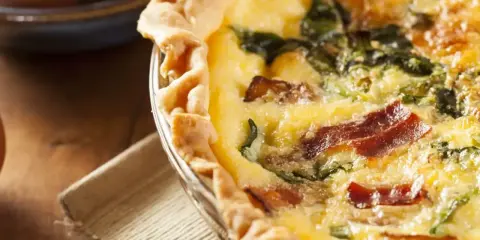 Une délicieuse tarte aux épinards et lardons, dorée et appétissante, prête à être dégustée.