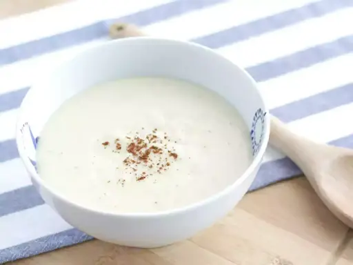 Un bol de sauce béchamel onctueuse, saupoudrée de noix de muscade râpée, prêt pour votre recette.
