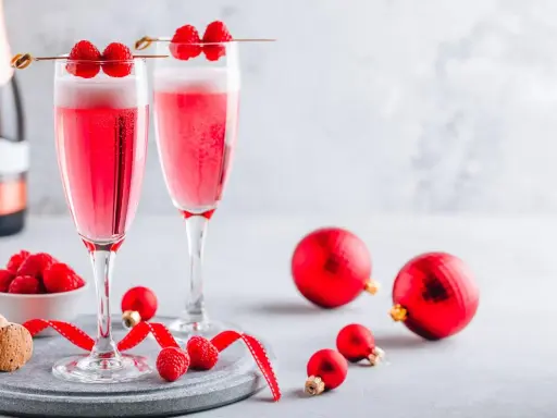 Deux coupes de soupe champenoise framboise pétillante, décorées de fruits rouges frais, prêtes pour les fêtes.