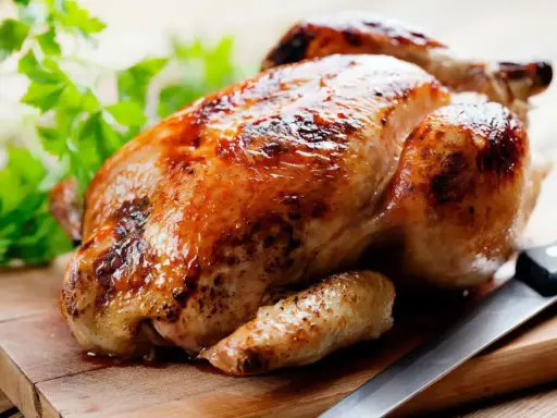 Un appétissant poulet rôti sur une planche en bois, prêt à être dégusté. Quel vin avec poulet rôti ? Un blanc fruité ou un rouge léger serait parfait.