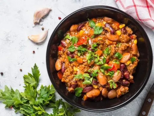 Un bol de chili sin carne, garni de persil frais. Des haricots rouges, du maïs et des dés de poivrons se mêlent à la viande hachée dans cette recette réconfortante.