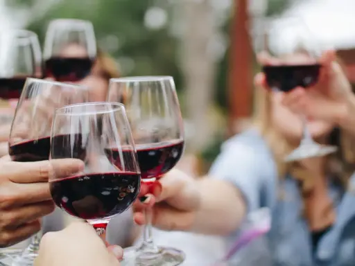 Des mains portent des verres de vin rouge pour un apéro convivial.