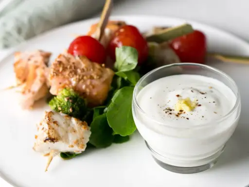 Brochettes de poisson et saumon grillés avec tomates cerises, brocolis et une sauce au yaourt crémeuse.