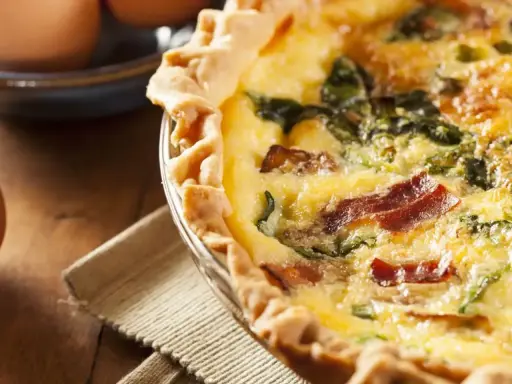 Une délicieuse tarte aux épinards et lardons, dorée et appétissante, prête à être dégustée.