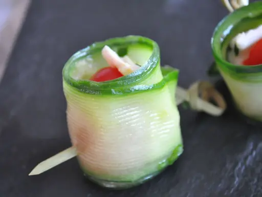 Délicieux wrap apéro de concombre garni de fromage frais, tomate cerise et herbes. Parfait pour un apéritif léger et coloré.