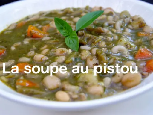 Un bol de soupe au pistou, garni de basilic frais, avec des haricots blancs, des pâtes et des carottes.