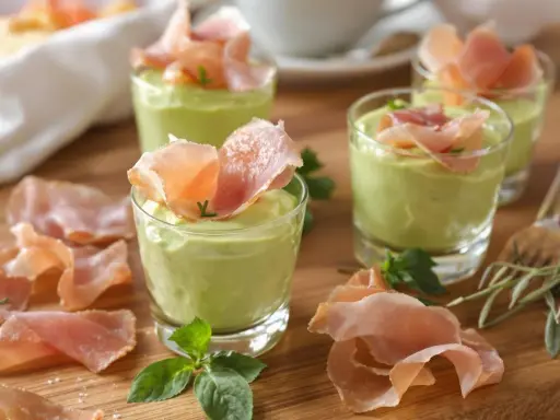 Petits verrines de mousse de chevre onctueuse, garnies de fines tranches de jambon cru et de quelques herbes fraîches.