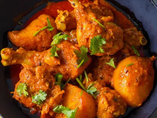Un plat appétissant de poulet et de pommes de terre en sauce curry, garni de coriandre fraîche. Un délice pour les amateurs de marinade poulet curry.