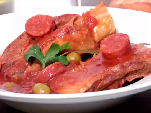 Plats de poitrine de veau mijotée, garnie de rondelles de chorizo, d'olives vertes et d'une feuille de laurier. Une recette savoureuse.