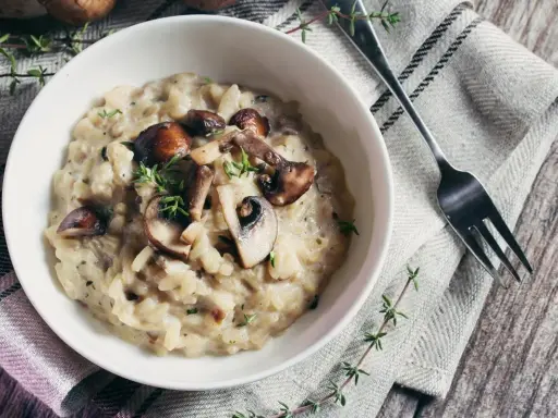Risotto crémeux aux champignons, garni de thym frais. Une alternative savoureuse au vin blanc pour un risotto parfait.