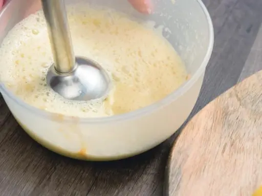 Préparation d'une recette mayonnaise maison avec un mixeur plongeant dans un bol. La texture commence à s'épaissir.