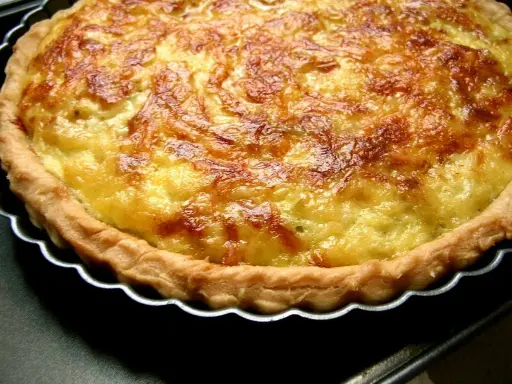 Une tarte aux poireaux dorée et appétissante, prête à être dégustée. Sa croûte croustillante et sa garniture onctueuse invitent au partage.