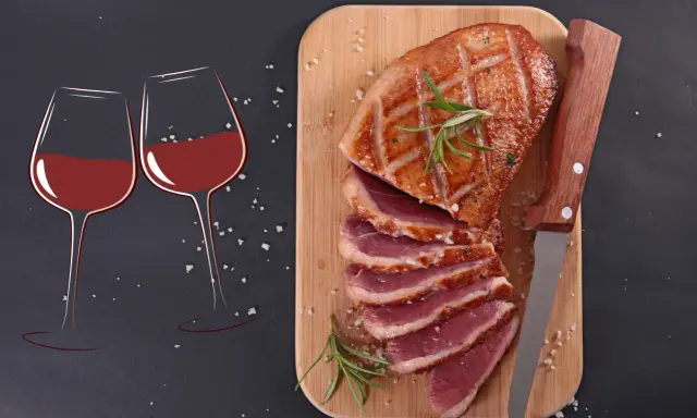 Quel vin avec magret de canard ? Deux verres de vin rouge et un magret de canard tranché sur une planche en bois, prêts à être dégustés.