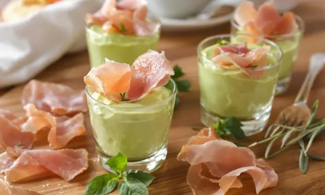 Petits verrines de mousse de chevre onctueuse, garnies de fines tranches de jambon cru et de quelques herbes fraîches.