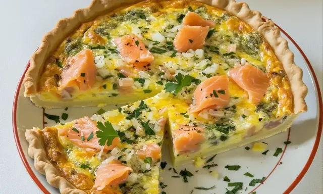 Une délicieuse quiche sans pâte grand-mère au saumon, oignons et persil, coupée en part.