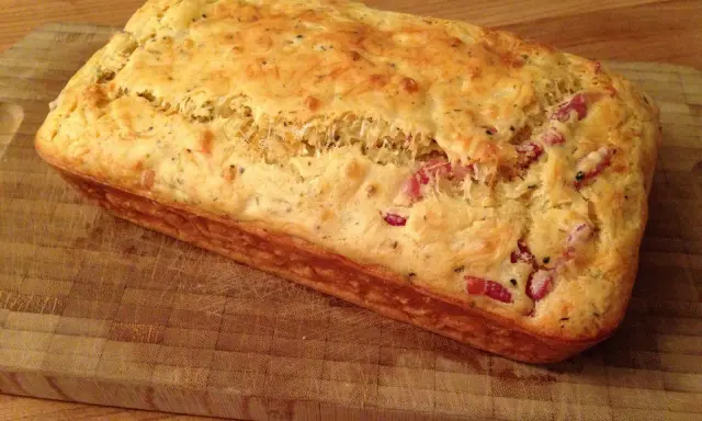 Un délicieux cake aux lardons, doré et moelleux, prêt à être dégusté sur une planche en bois.