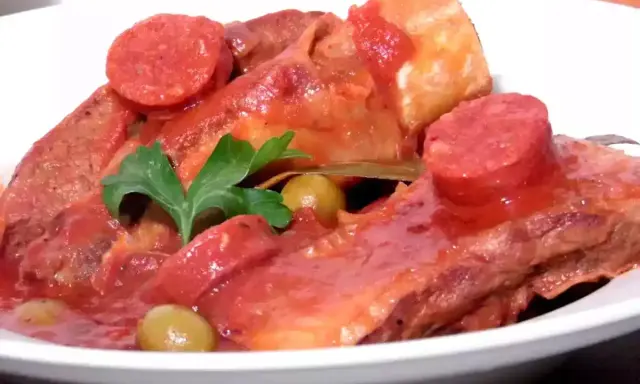 Plats de poitrine de veau mijotée, garnie de rondelles de chorizo, d'olives vertes et d'une feuille de laurier. Une recette savoureuse.