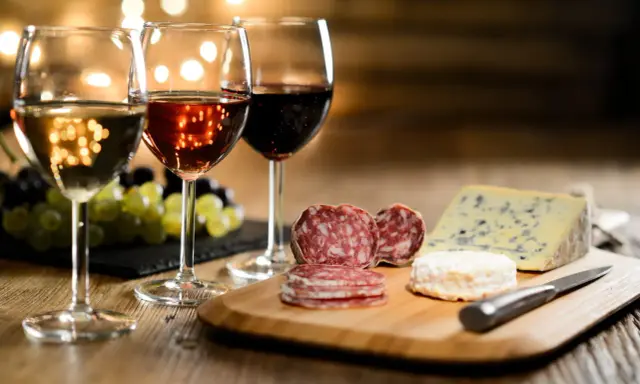 Trois verres de vin, blanc, rosé et rouge, accompagnent un plateau de fromages et charcuteries. La question est : quel vin avec le fromage ?