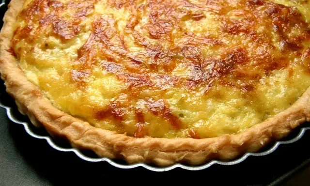 Une tarte aux poireaux dorée et appétissante, prête à être dégustée. Sa croûte croustillante et sa garniture onctueuse invitent au partage.