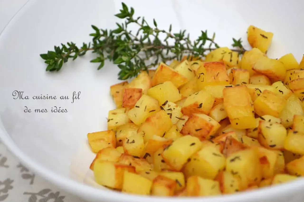 Un plat de pomme de terre saut&eacute;es dor&eacute;es et croustillantes, parsem&eacute;es d'herbes, avec une branche de thym frais.