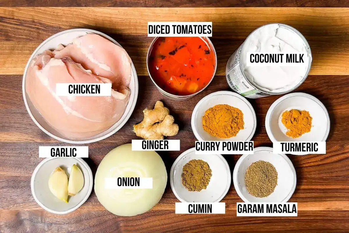 Ingrédients pour une marinade poulet curry : poulet cru, lait de coco, tomates concassées, oignon, ail, gingembre, poudre de curry, curcuma, cumin et garam masala.