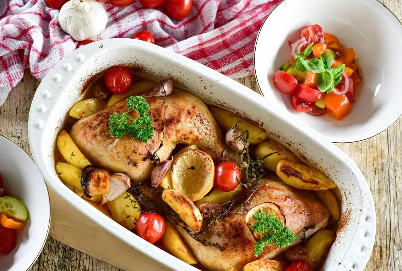 Délicieuse cuisse de poulet au four, dorée et juteuse, accompagnée de pommes de terre rôties, tomates cerises et ail.