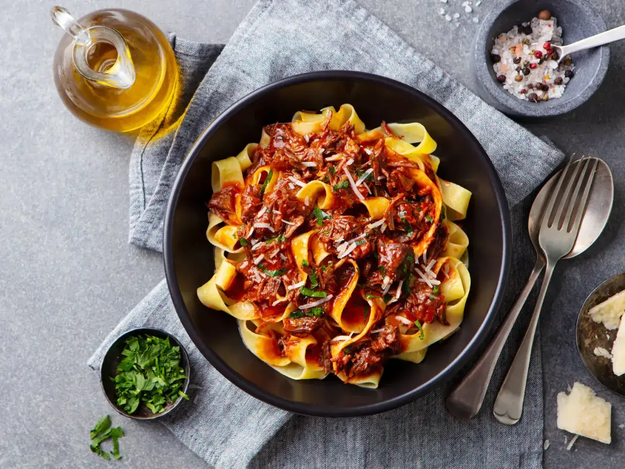 Pâtes fraîches nappées d'une riche sauce bolognaise maison, parsemées de parmesan et de persil. Un délice !