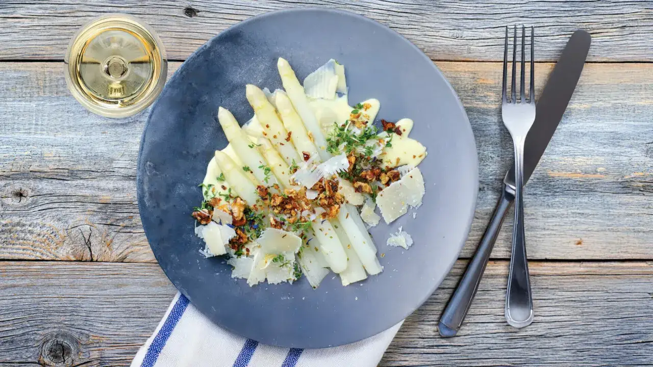 Asperges blanches nappées d'une onctueuse sauce mousseline, garnies de noix croquantes et de copeaux de parmesan. Un délice printanier.