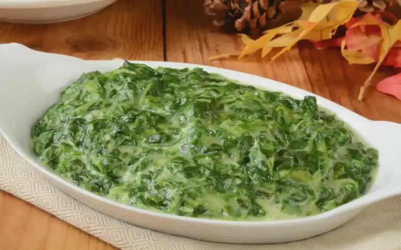Un plat de épinards à la crème crémeux et appétissant dans un plat blanc, prêt à être dégusté.